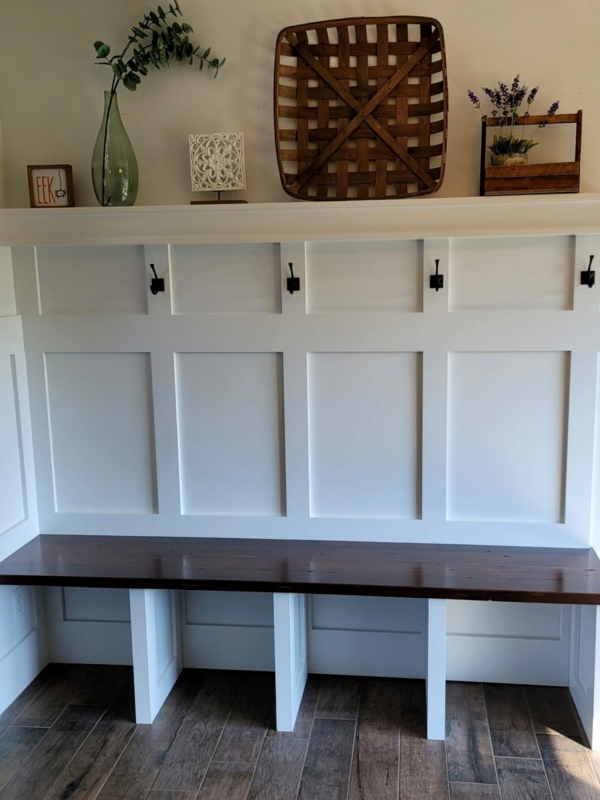 Mudroom bench with a seat made from the home’s original 1930s pine floorboards. Custom mudroom bench with a seat made from reclaimed 1930s pine flooring from the same home, painted panel wall and coat hooks, built by Travis at Thirty Three Cabinetry